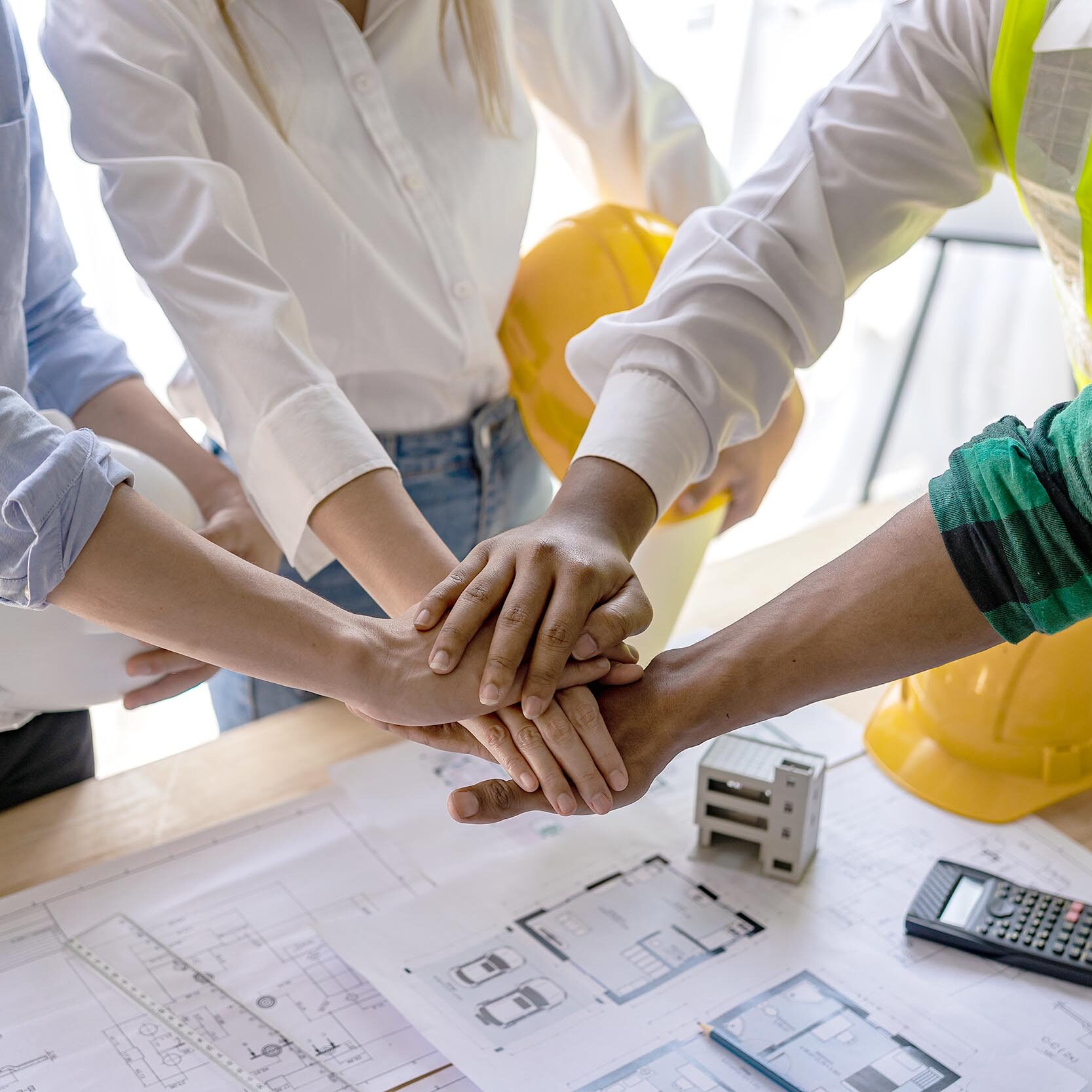 Construction workers holding helmets and vests are shaking hands Construction workers holding helmets and vests are shaking hands